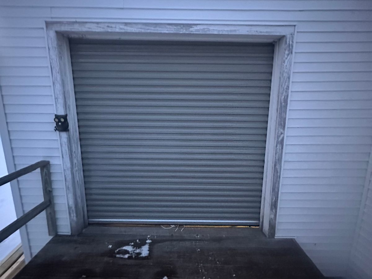 Weathered commercial rollup door on vinyl-sided building exterior